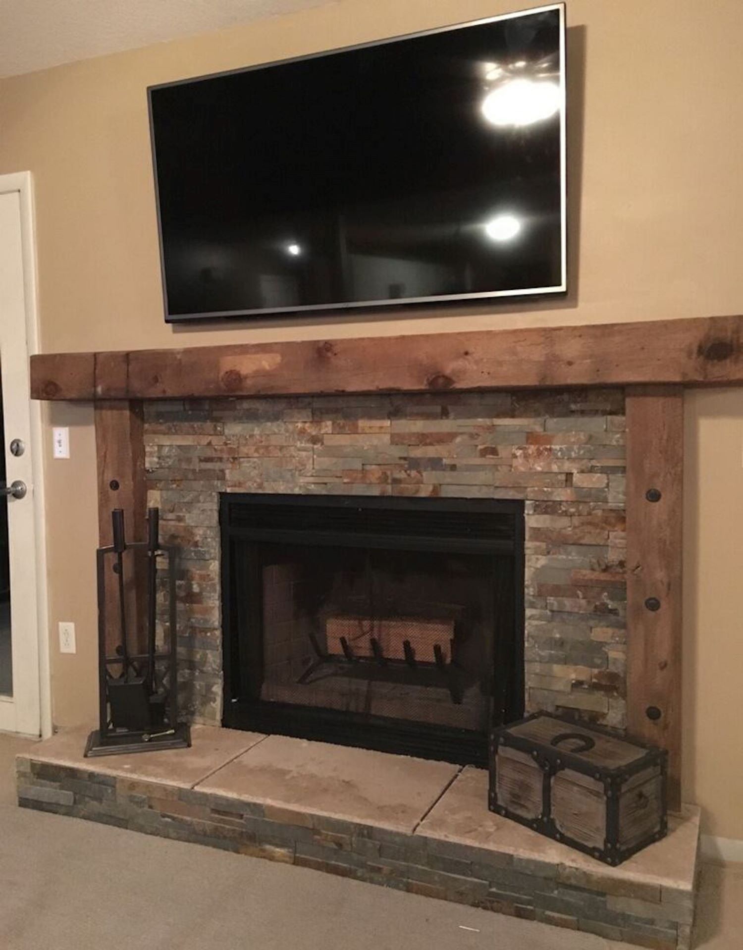 Barn beam mantle above a stone fireplace