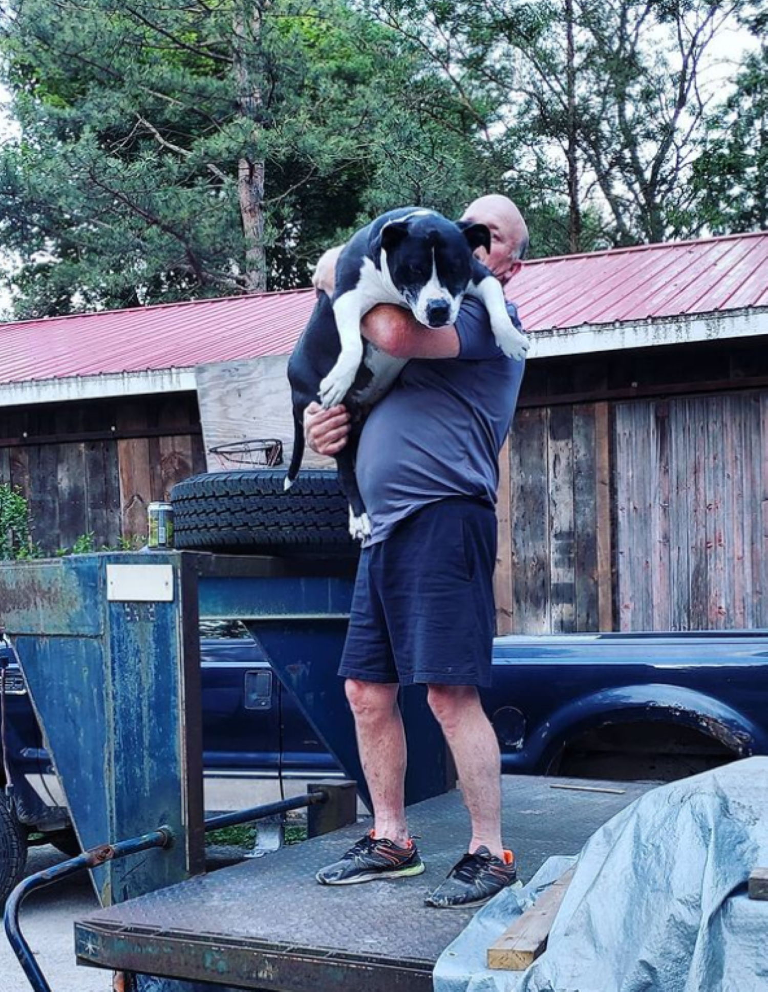 Jim holding Midnite, one of the shop dogs, outside the shop.