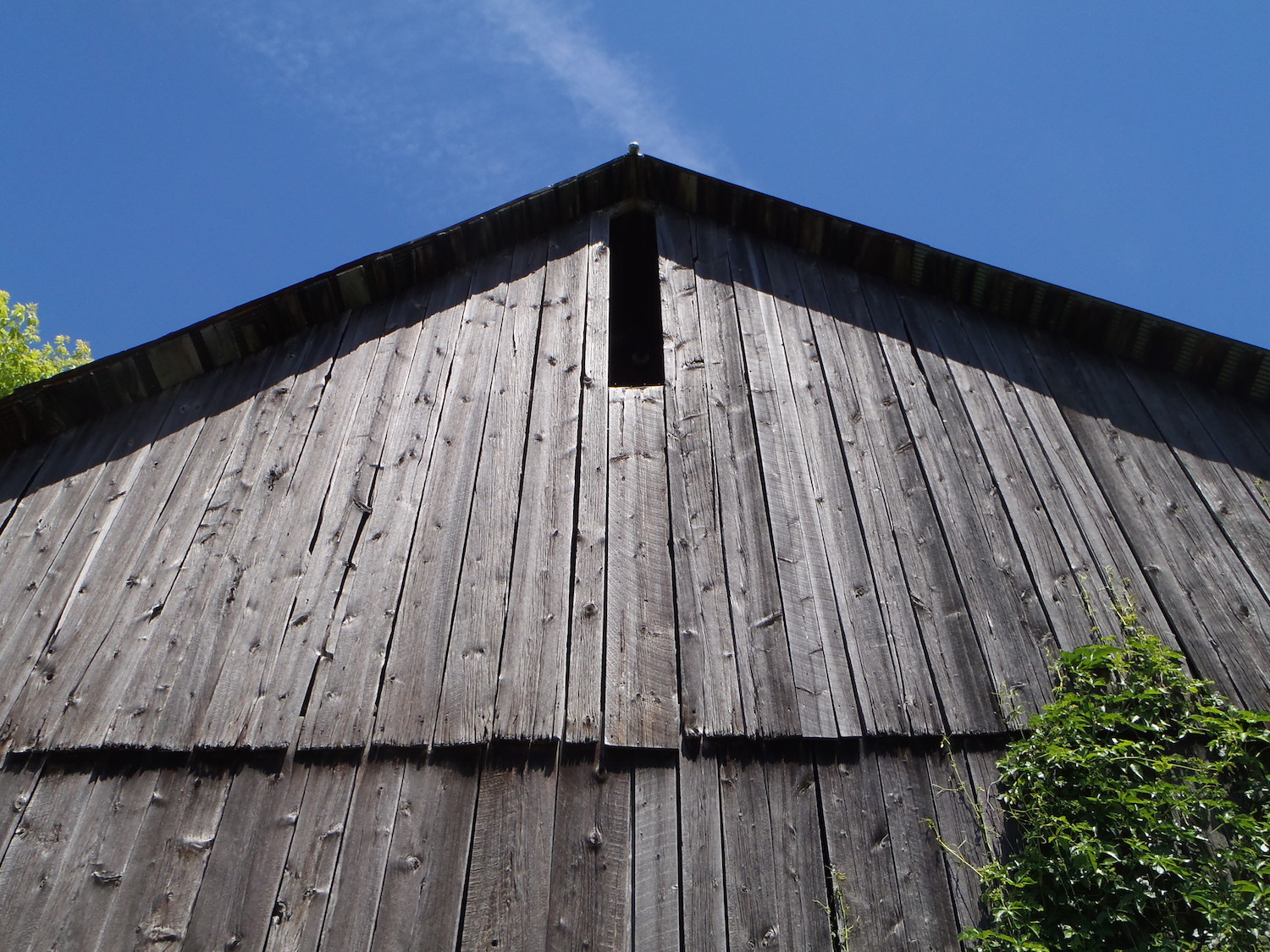 A grey barn with a ggable roofline located in Alpena, Michigan