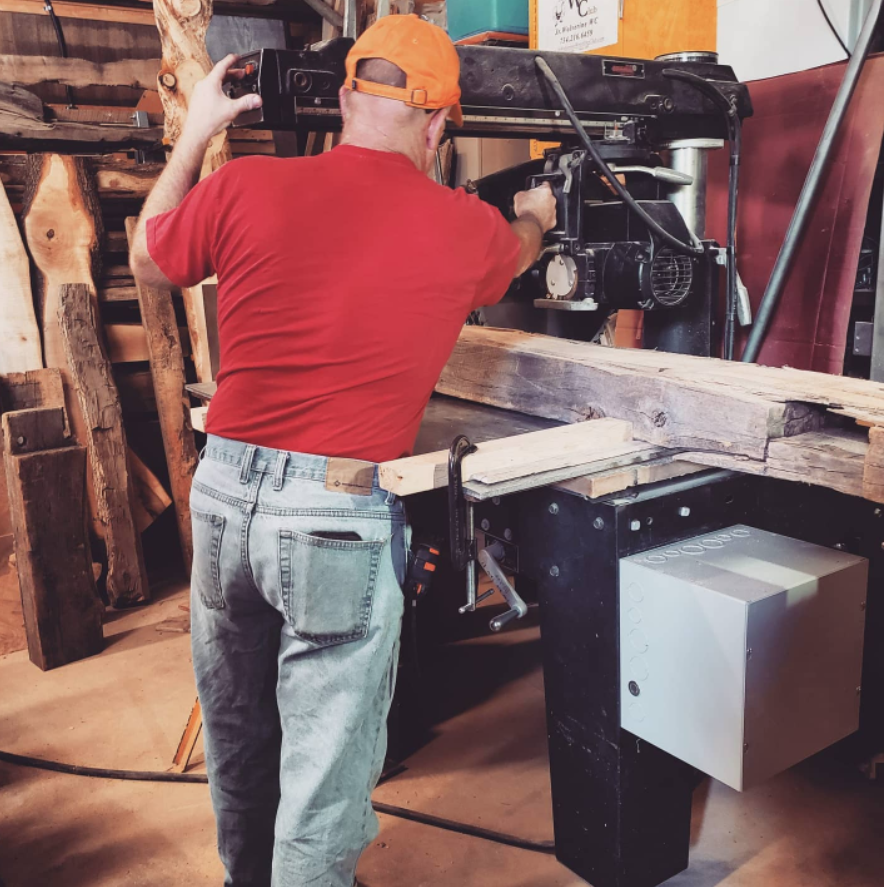 Jim has his back to the camera while he operates a table saw in his workshop