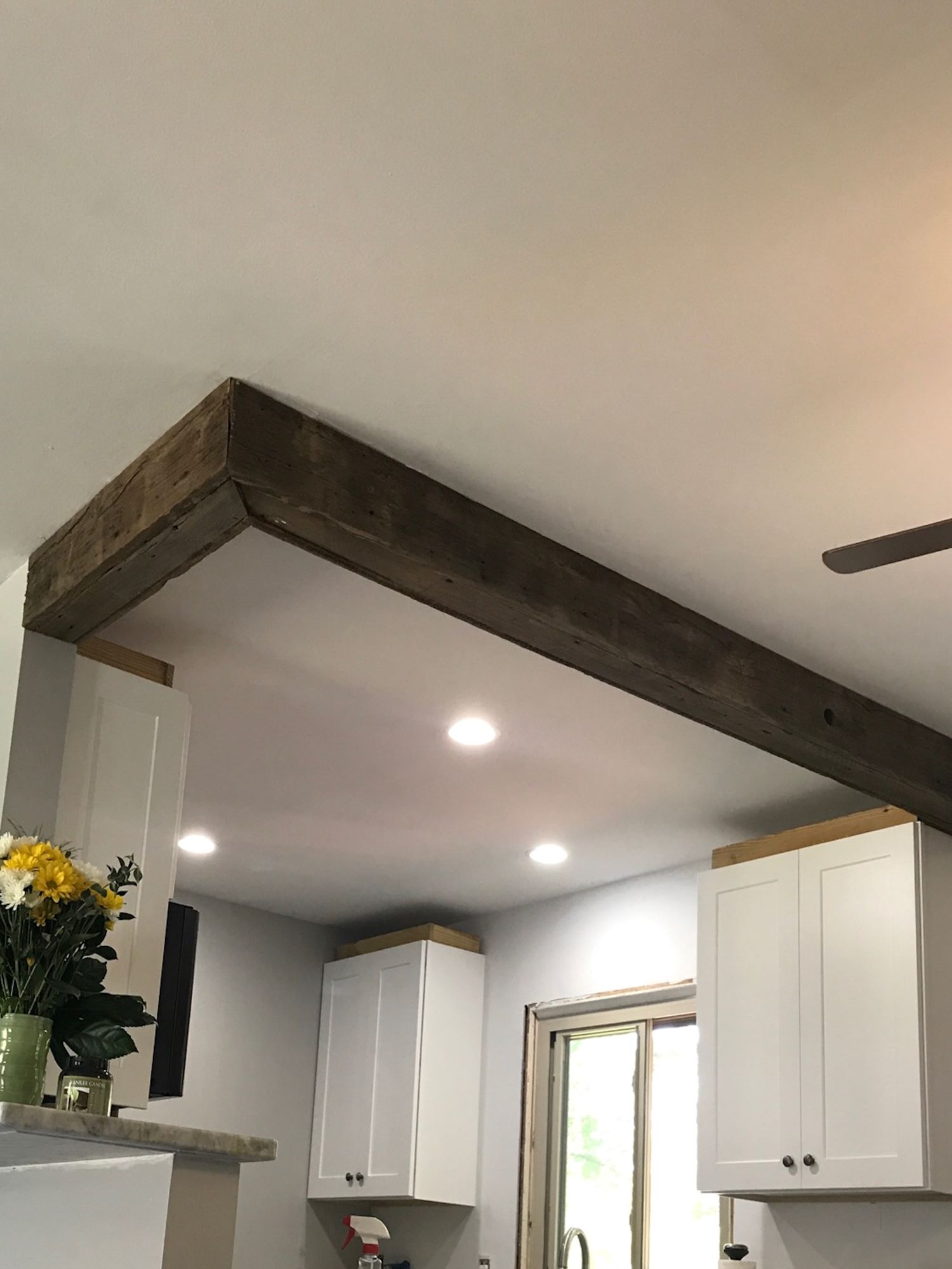 A brown reclaimed accent beam above a customer's kitchen