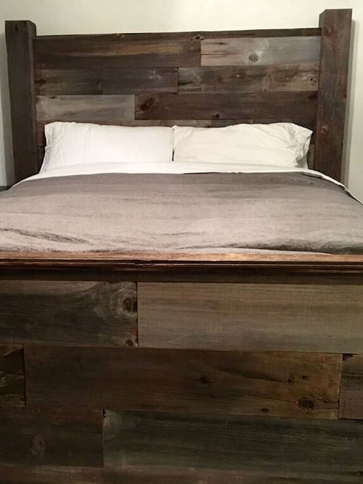 A custom made headboard crafted from brown reclaimed barnwood