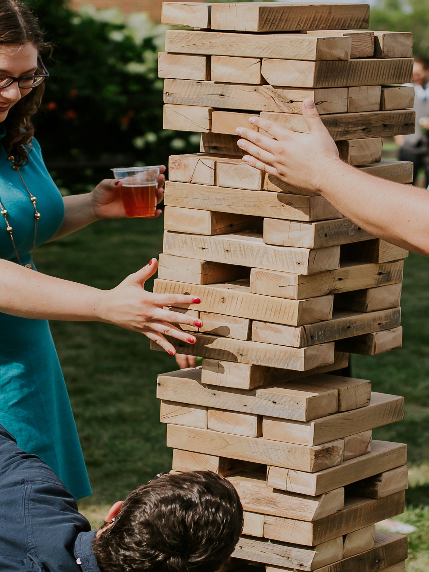 A giant jenga set in use at an ourdoor wedding