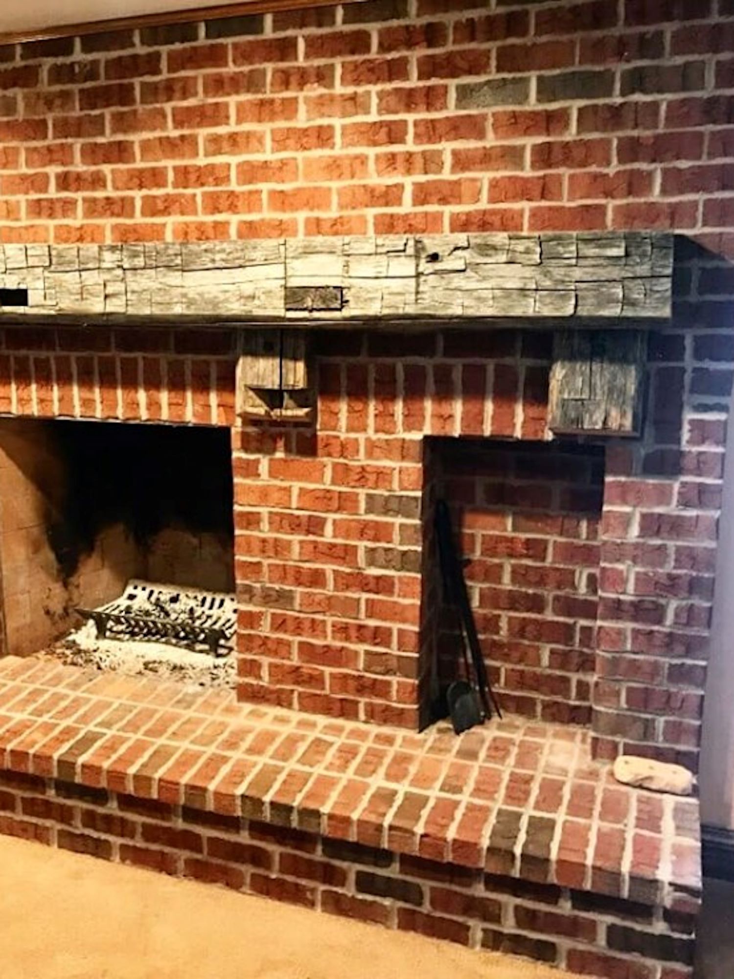 Hand hewn barn beam mantle on a red brick fireplace